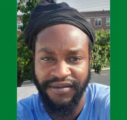 Man wearing blue shirt and black headwrap, outdoor portrait