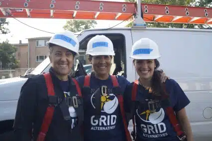 Three We Build volunteers pose by a truck