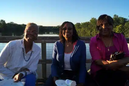 Two potential clients and one current GRID client sit by the river.
