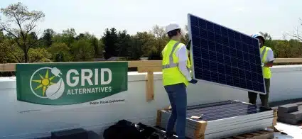 Two Constellation volunteers carry a solar panel