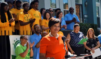 Community event with diverse group wearing yellow and blue shirts, child in orange shirt at center