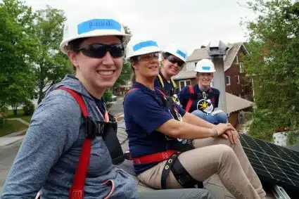 Four volunteers pose on the roof of the home while installing solar