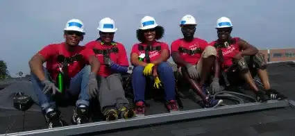 Five Wells Fargo volunteers sit on a roof, taking a break