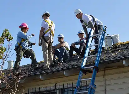 Amaris, in pink hardhat, teaching volunteers about wiring at a recent install.