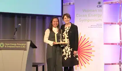 Two women on stage at Women in Clean Energy Symposium, holding an award