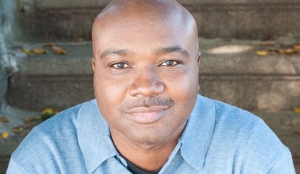 Portrait of a man in a light blue shirt against a wooden background