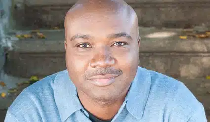 Portrait of a man in a light blue shirt against a wooden background
