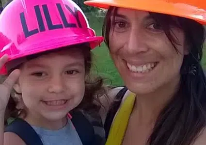 Chrissy and her daughter Lilly smile for the camera with their hard hats on.