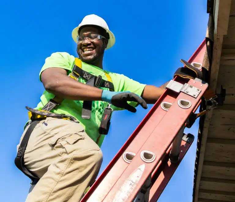 Darnell Asberry climbing ladder to work on the roof