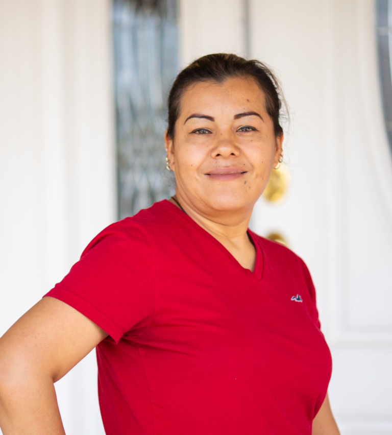 Woman wearing red v-neck shirt smiling at camera against white background