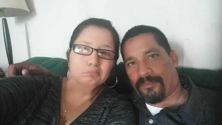 Two people sitting on a green couch taking a selfie together indoors