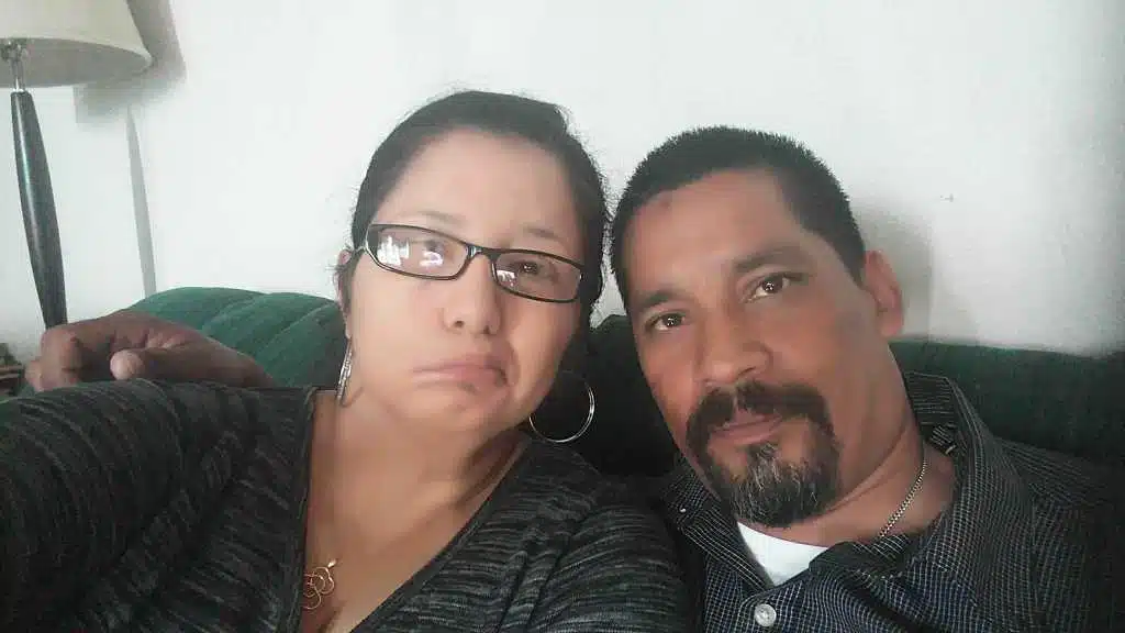 Two people sitting on a green couch taking a selfie together indoors