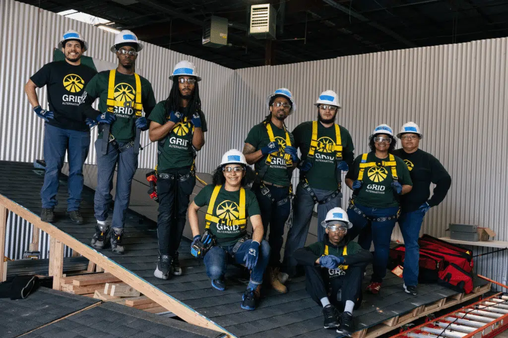 A GRID crew in safety harnesses poses together on a rooftop under construction.
