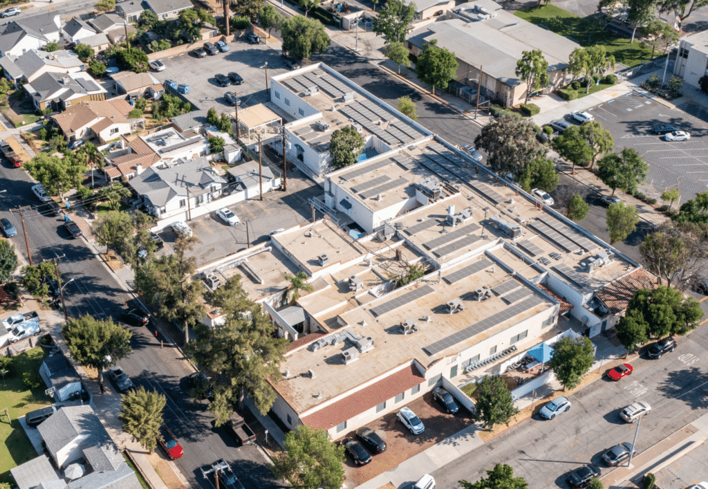 Aerial view of a large community building with solar panels covering its rooftop.
