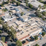 Aerial view of a large community building with solar panels covering its rooftop.