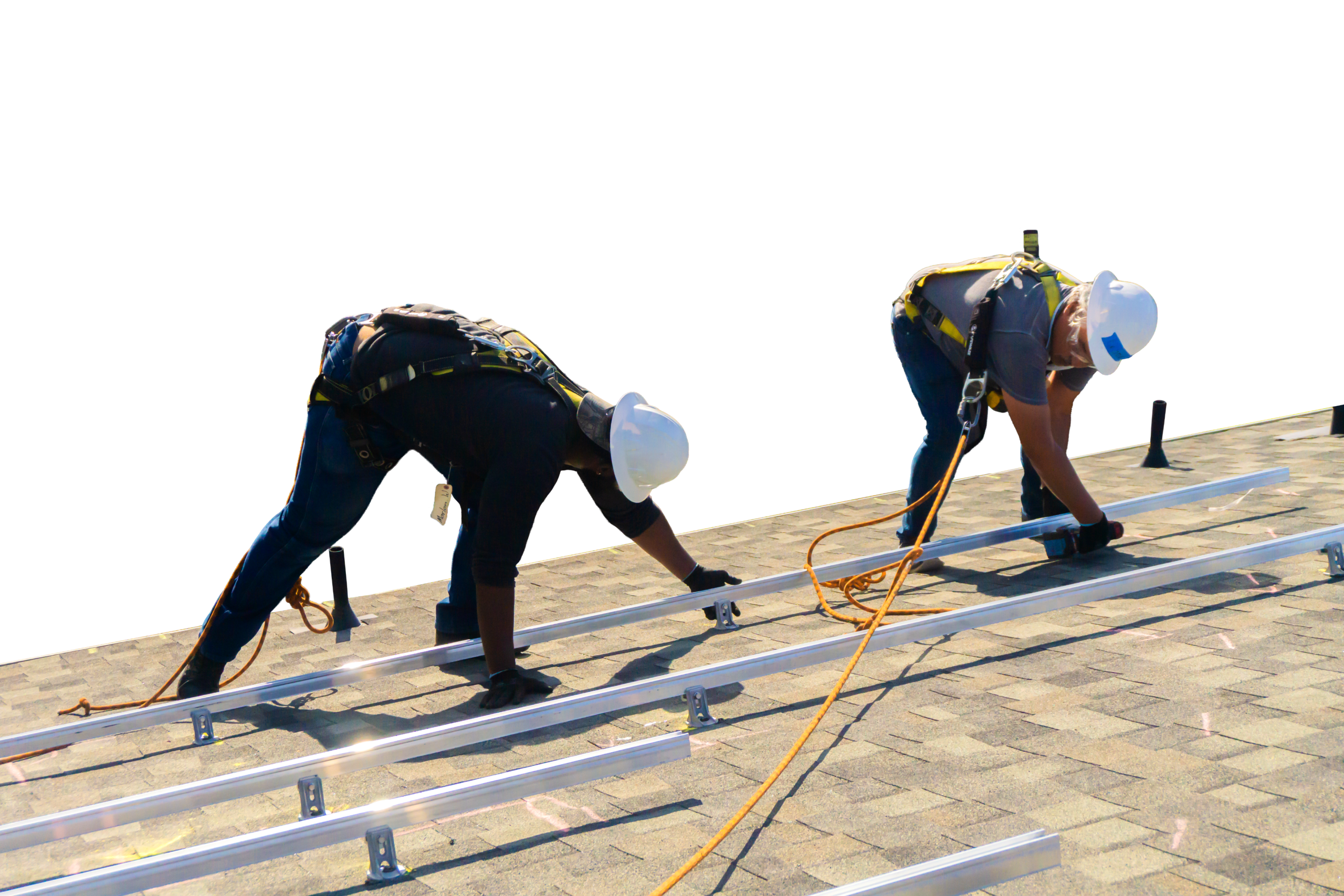 Two installers on a rooftop, silhouetted against a black backdrop, set mounting rails into place.