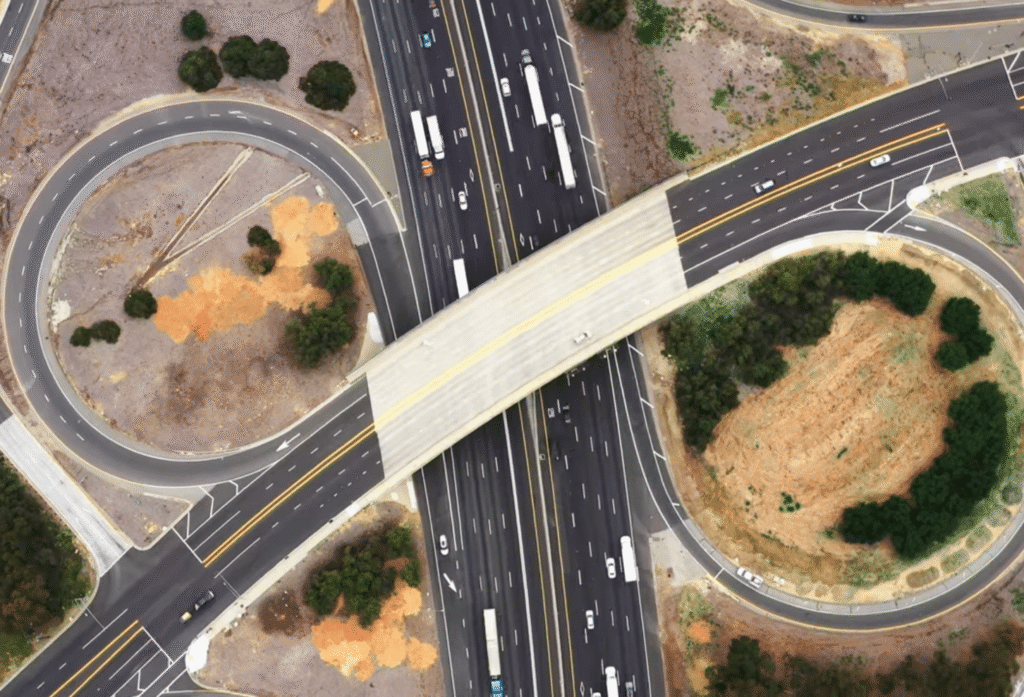 Aerial view of a highway cloverleaf interchange with an overpass crossing multiple lanes of traffic.