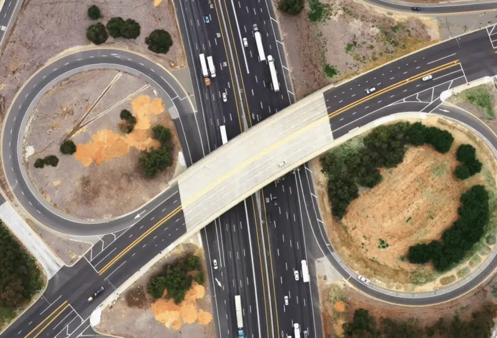 Aerial view of a highway cloverleaf interchange with an overpass crossing multiple lanes of traffic.