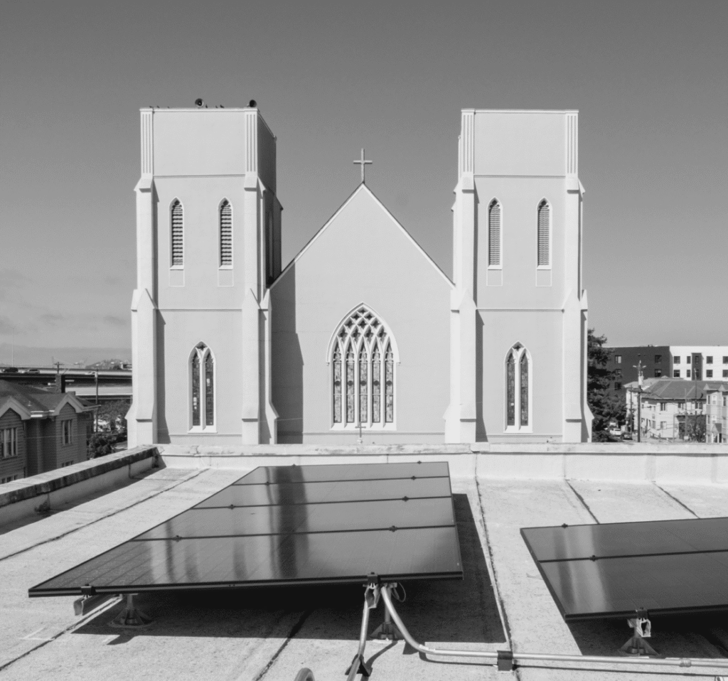 Solar panels cover the roof of a church building under a clear blue sky.