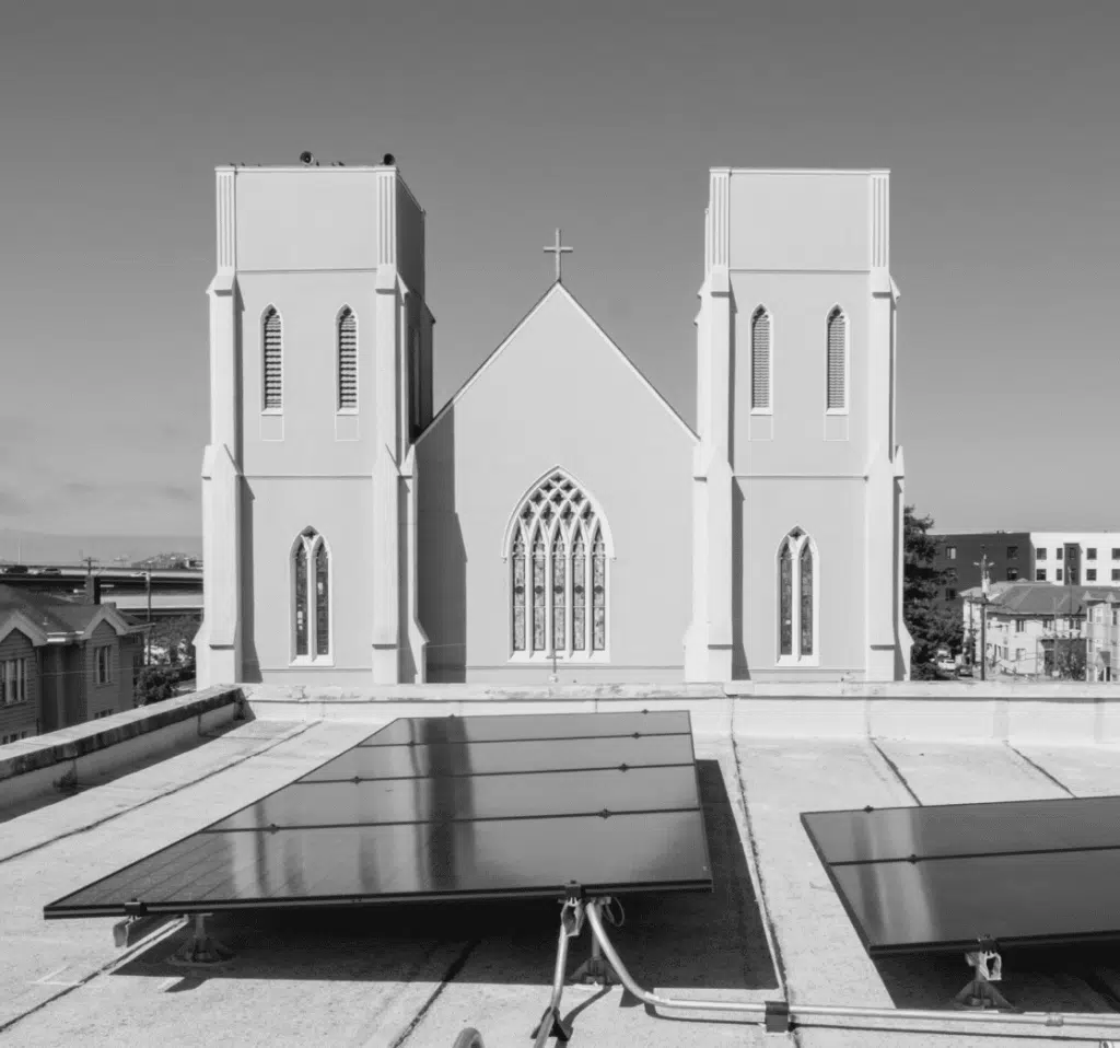 Solar panels cover the roof of a church building under a clear blue sky.