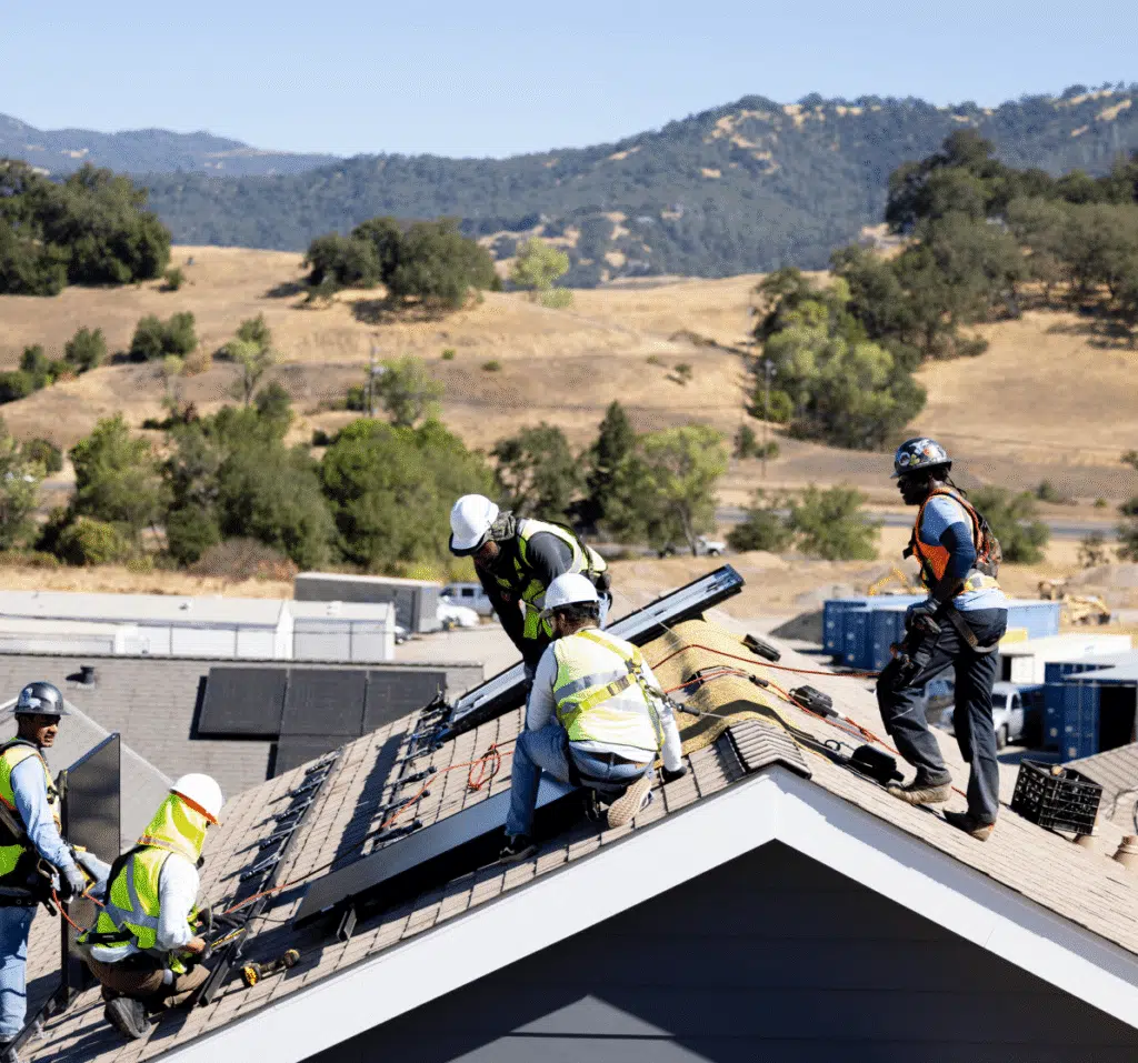 A team of installers gathers on a hillside multifamily rooftop during a solar install.