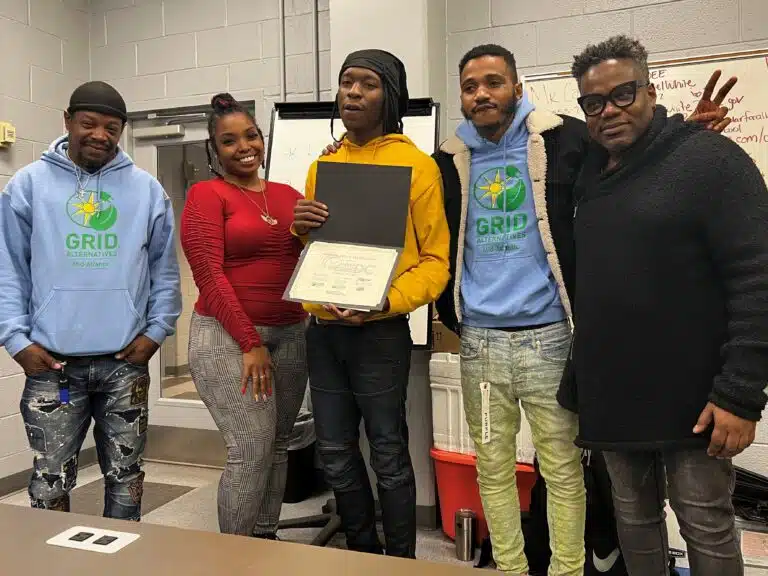 Khalil holds his certificate after graduating from the Solar Works DC program.