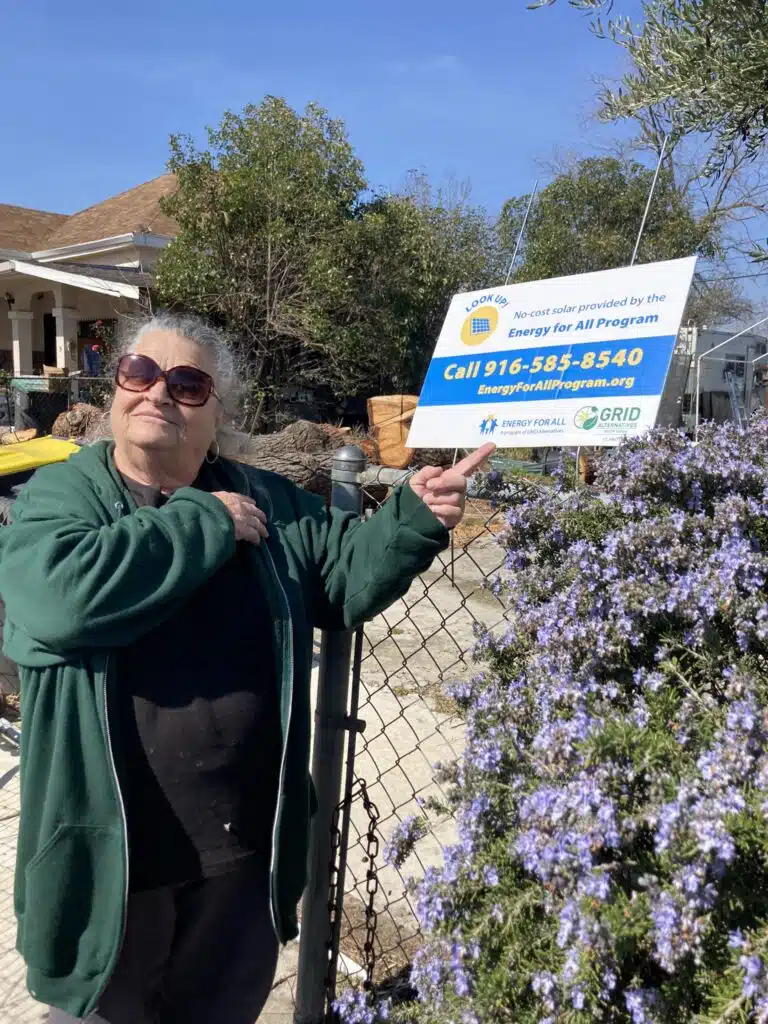 Stockton resident and GRID client Patricia Barret in front of Energy for All lawn sign