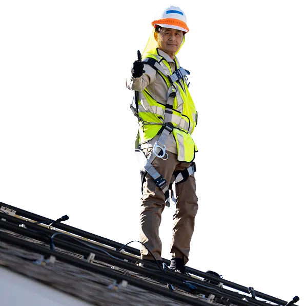 Construction worker on roof wearing safety gear gives thumbs up