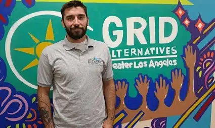Man standing in front of GRID Alternatives Greater Los Angeles colorful mural with hands design