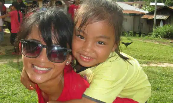 Woman and young child smiling together outdoors in a grassy area