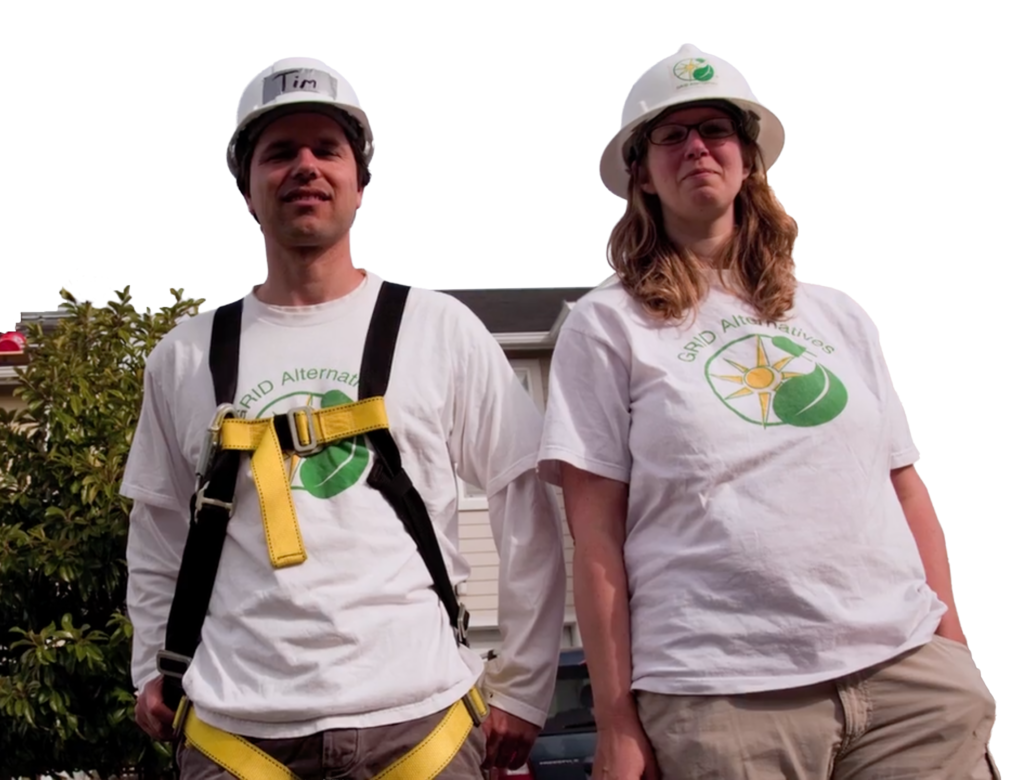 GRID Alternatives co-founders Erica Mackie and Tim Sears in hard hats and GRID Alternatives t-shirts, standing beside a company truck.