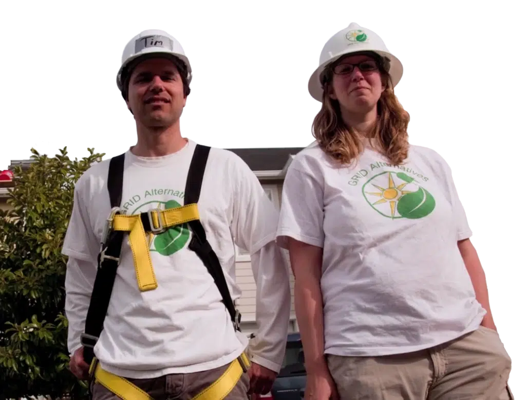 GRID Alternatives co-founders Erica Mackie and Tim Sears in hard hats and GRID Alternatives t-shirts, standing beside a company truck.