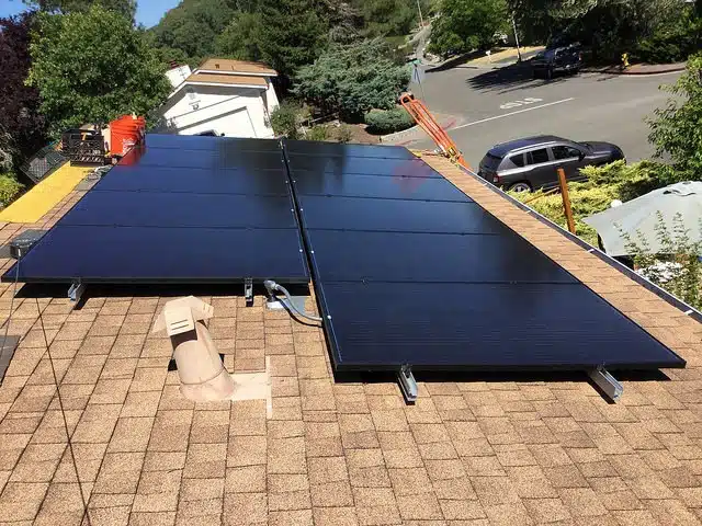 Solar panels installed on a residential roof with mounting hardware and electrical conduit visible