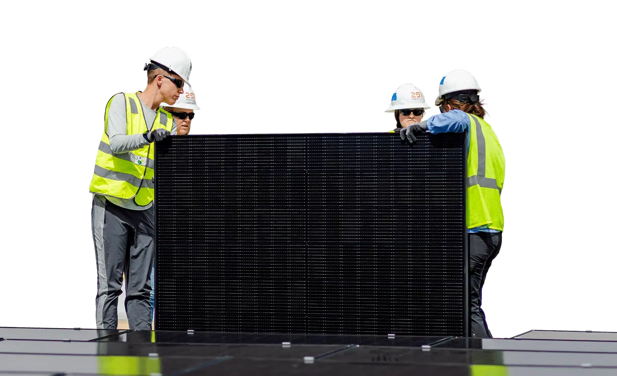 Four workers in safety gear installing a solar panel on a roof