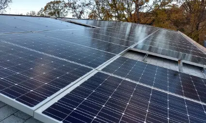 Solar panels installed on a residential roof with trees in the background