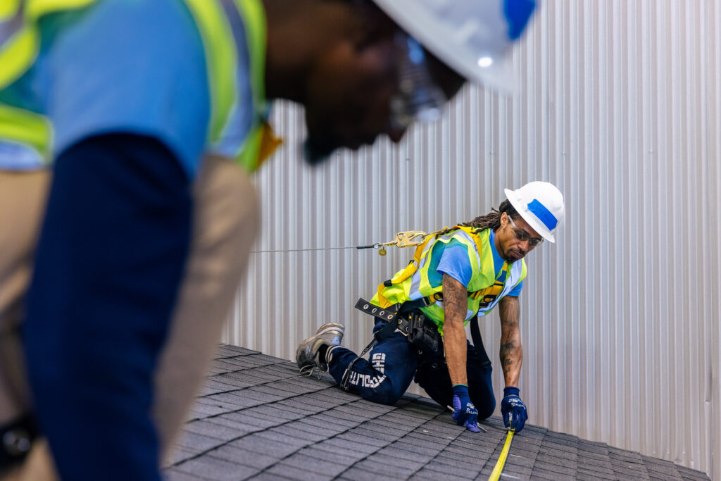 Construction worker in safety gear practices rope rescue training on roof