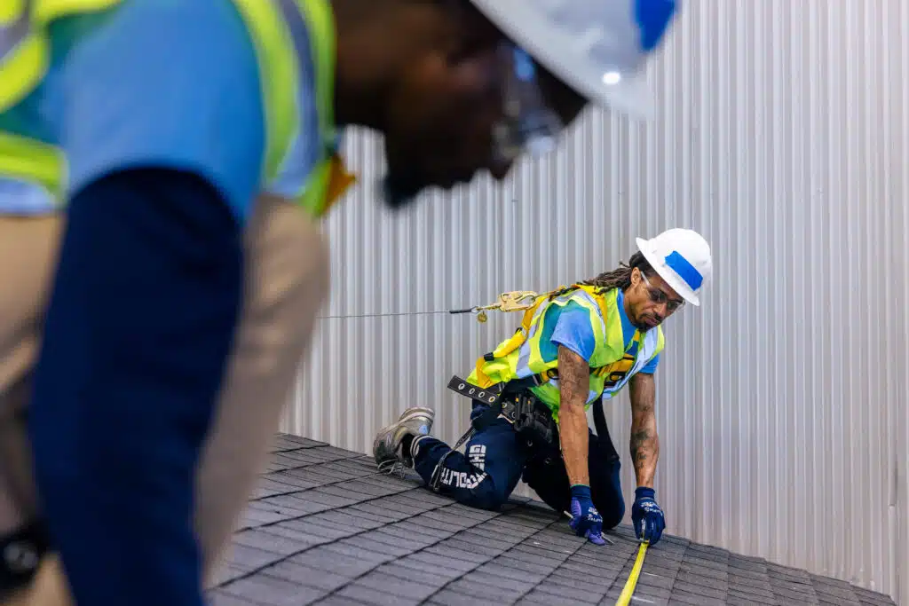 Construction worker in safety gear practices rope rescue training on roof