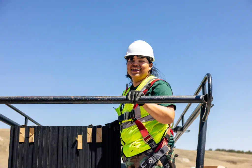 Worker in safety helmet and harness holding electrical wires at residential installation site