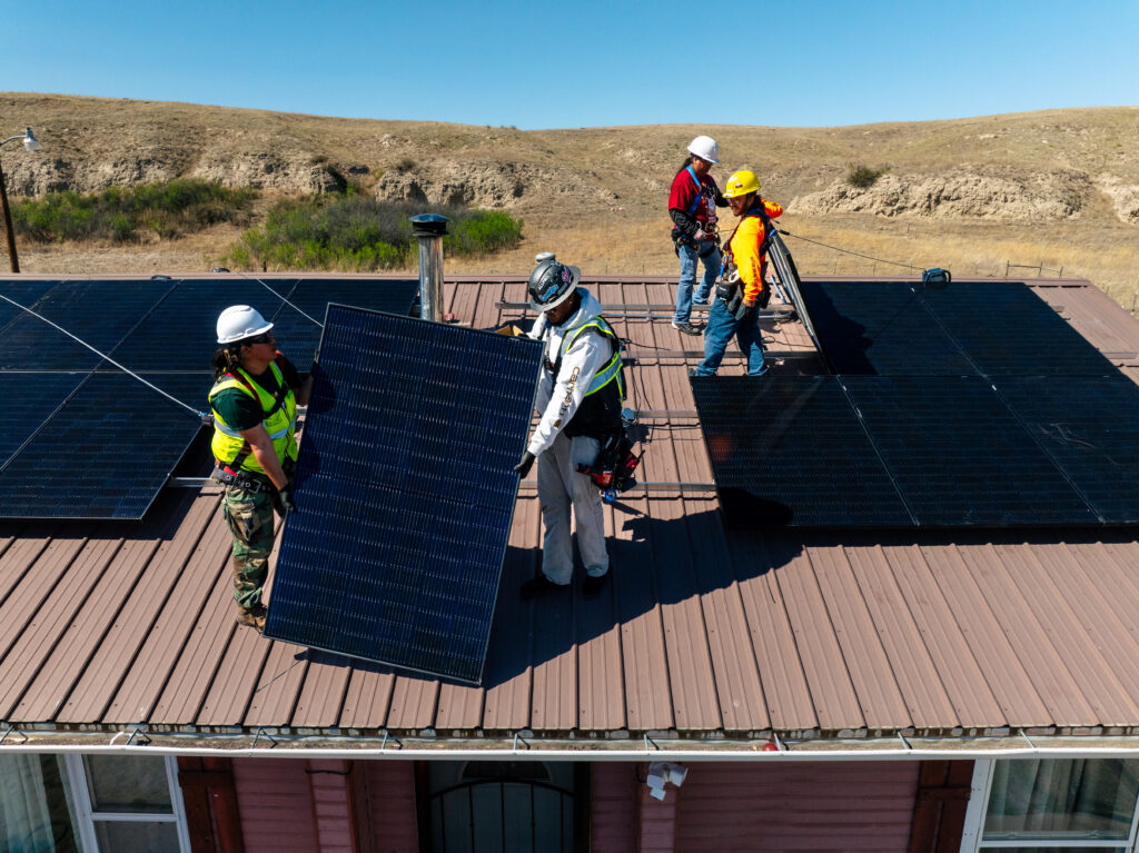 tribal solar installation, panels on roof with 4 installers