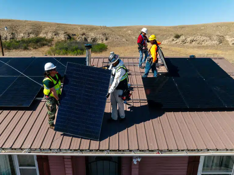 tribal solar installation, panels on roof with 4 installers