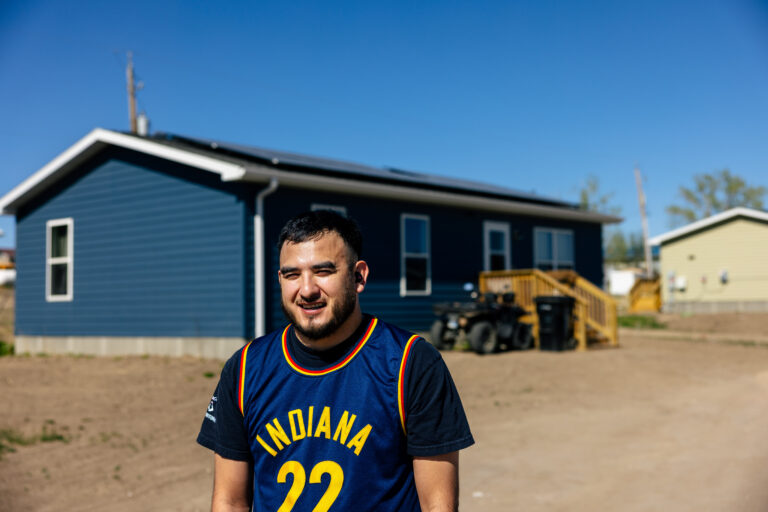 Man wearing Indiana Pacers jersey standing in front of blue mobile home
