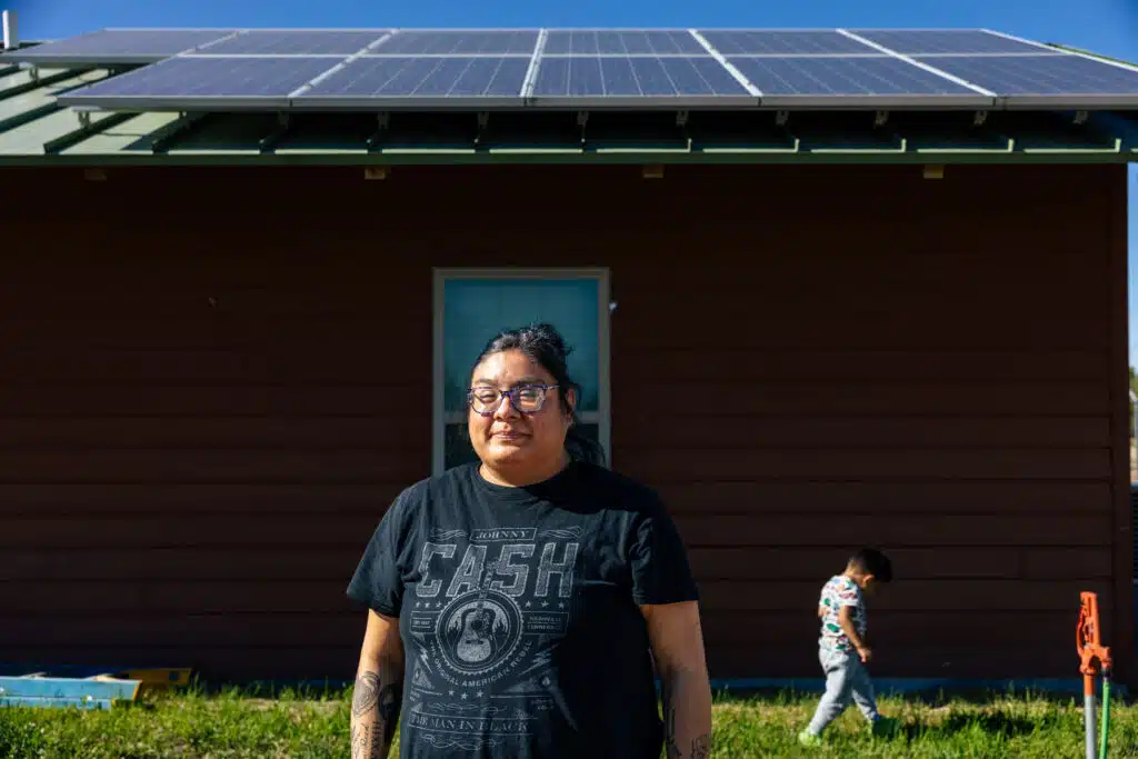 Woman standing in front of her home with rooftop solar