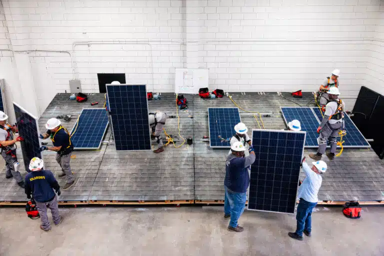 Solar panels on training roof, with installers and safety equipment