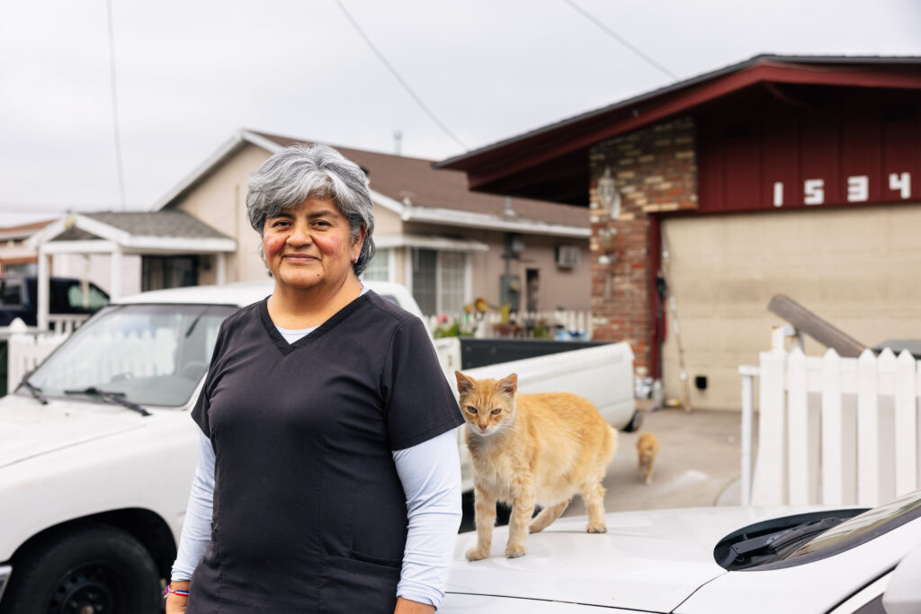 Woman standing in driveway with orange cat, residential neighborhood behind her