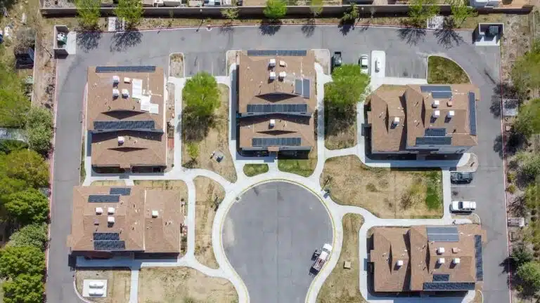 Aerial view of residential neighborhood with six brown-roofed houses arranged around a central circular cul-de-sac with solar panels on roofs