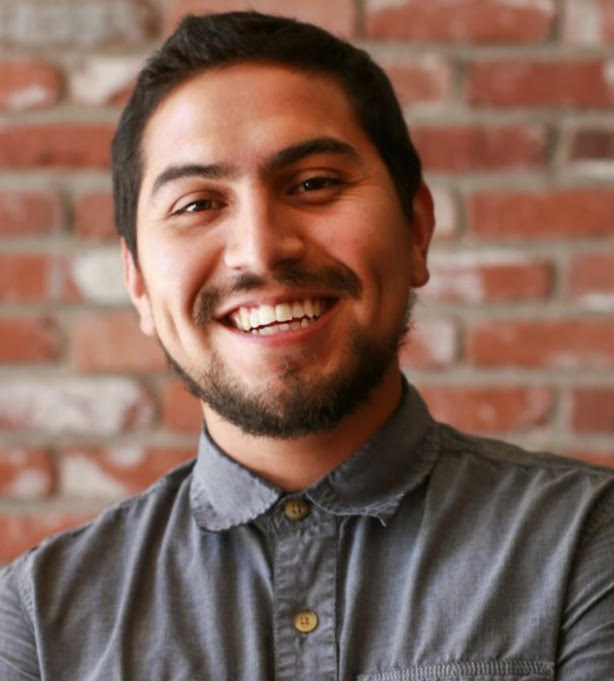 Edgar Arellnao smiling against a brick wall