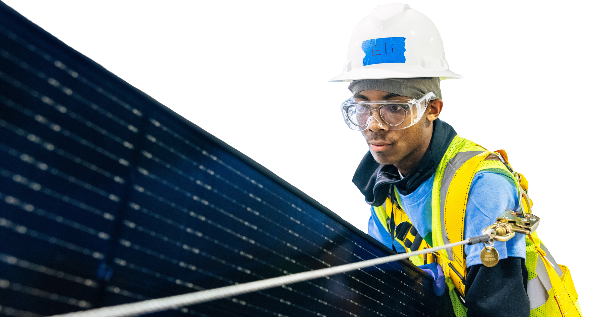 Worker in safety gear holding solar panel cable against dark panel