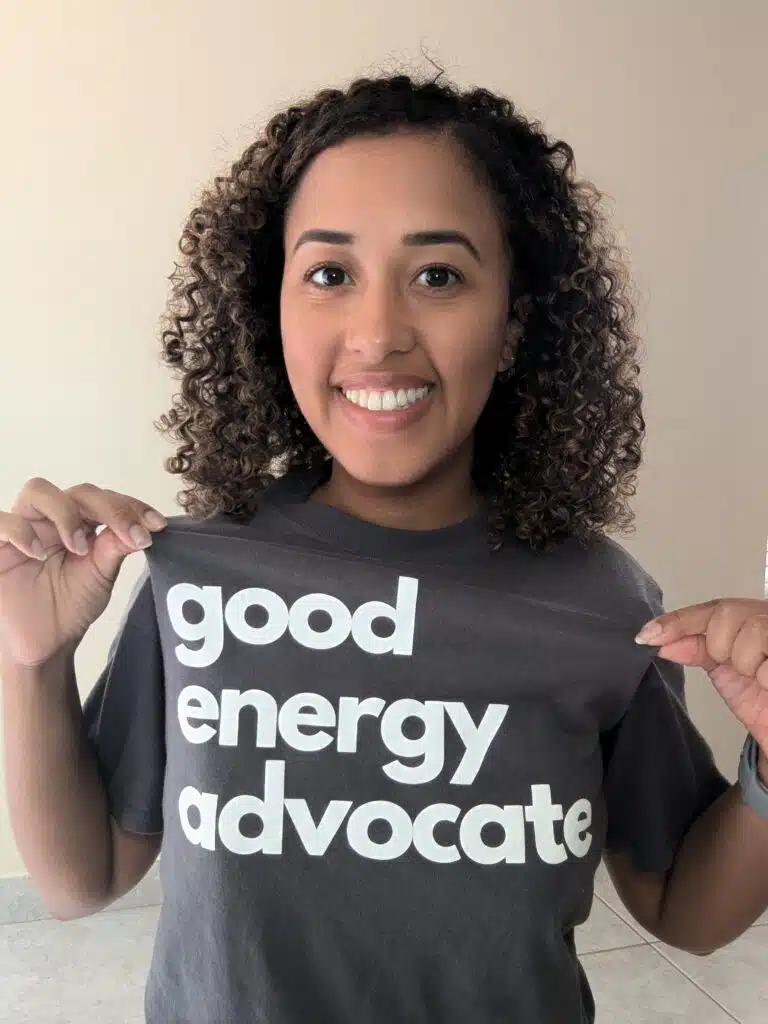 Smiling woman wearing a dark gray t-shirt that reads "good energy advocate