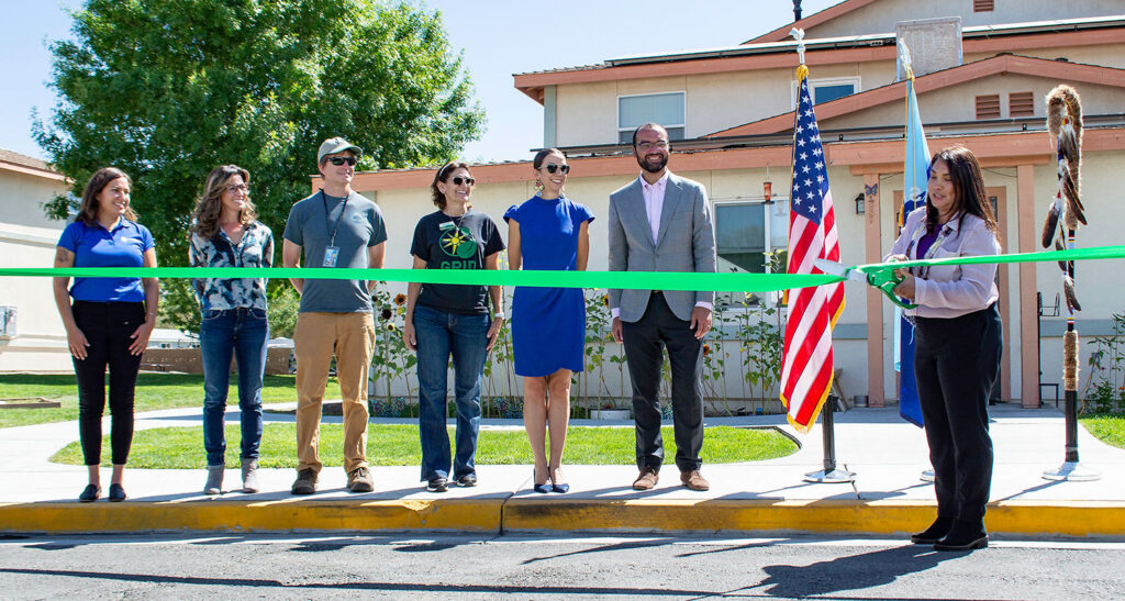 Group of people at ribbon-cutting ceremony for Coyote Mountain Apartments with American flag
