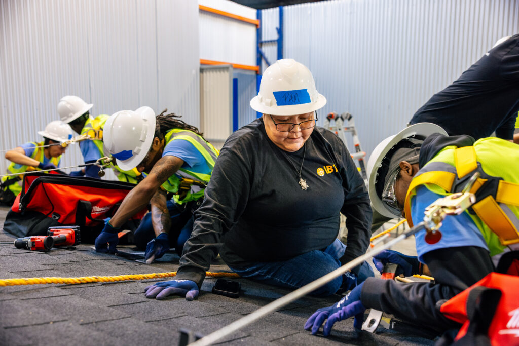 Construction workers in safety gear practicing rope handling during IBT training in warehouse